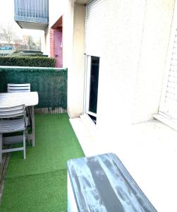 a patio with a table and a green lawn at Capsule Miami Vice - Jacuzzi - Billard - Ecran cinéma & Netflix - Ping-Pong - Nintendo & Jeux- in Liévin