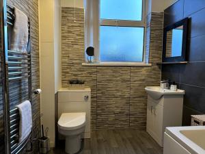 a bathroom with a toilet and a sink and a window at Stratford Stay - sleeps up to 9 near City Centre with parking in Birmingham