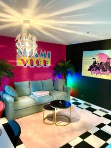 a living room with a couch and a table at Capsule Miami Vice - Jacuzzi - Billard - Ecran cinéma & Netflix - Ping-Pong - Nintendo & Jeux- in Liévin