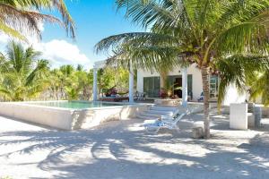 a house on the beach with a pool and palm trees at Telchac Beach House in Telchac Puerto