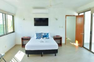 a bedroom with a bed and a tv on the wall at Telchac Beach House in Telchac Puerto