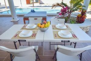 - une table blanche avec des chaises et un bol de fruits dans l'établissement Telchac Beach House, à Telchac Puerto