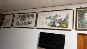 a wall with four framed paintings and a tv at 養生無憂村 採果樂 再送藝術扇子 in Chaozhou