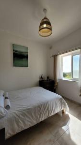 a white bedroom with a bed and a window at Luxury en-suite Double. Beach-house with Sea Views in Mellieħa