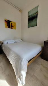 a bed in a bedroom with two pictures on the wall at Luxury en-suite Double. Beach-house with Sea Views in Mellieħa