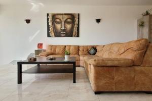 a living room with a brown couch and a table at Luxury en-suite Double. Beach-house with Sea Views in Mellieħa