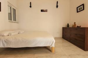 a bedroom with a bed and a wooden dresser at Luxury en-suite Double. Beach-house with Sea Views in Mellieħa