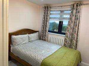 Schlafzimmer mit einem Bett und einem Fenster in der Unterkunft Modern Family Home in Greater London in Pinner