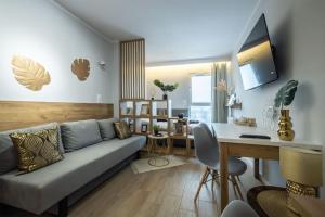 - un salon avec un canapé, une table et un bureau dans l'établissement WiguryTower Apartaments 67', à Łódź
