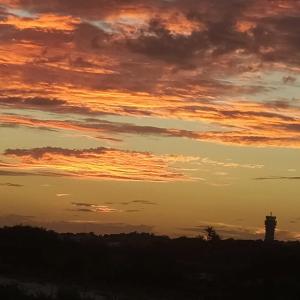 un coucher de soleil avec une tour de contrôle dans le ciel dans l'établissement Suíte Porto das Dunas, à Salvador