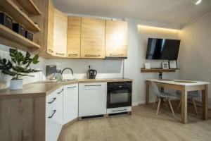 a kitchen with white cabinets and a table and a desk at WiguryTower Apartaments 68' in Łódź