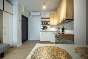 WiguryTower Apartaments 68' في لودز: مطبخ مع دواليب بيضاء وطاولة في الغرفة