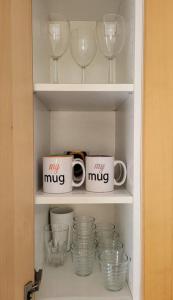 two mugs and glasses are sitting on a shelf at Oeiras Historic Bedrooms in Oeiras +68 photos