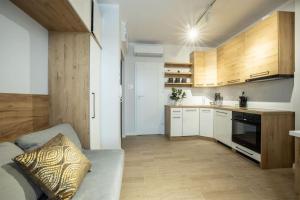 WiguryTower Apartaments 68' في لودز: مطبخ مع دواليب بيضاء واريكة في الغرفة