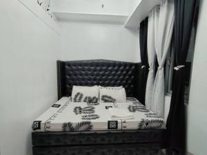 Schlafzimmer mit einem Bett mit einem schwarzen Kopfteil und Vorhängen in der Unterkunft Affordable Condo Unit in a Prime and Five-Star Location in Manila