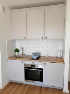 a kitchen with white cabinets and a sink at Nowy w centrum 2 in Giżycko