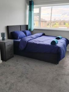 1 dormitorio con 2 camas con sábanas azules y ventana en Cosy Brighouse 3 bed house-Great for contractors, en Brighouse