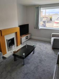 a living room with a fireplace and a tv at Cosy Brighouse 3 bed house-Great for contractors in Brighouse