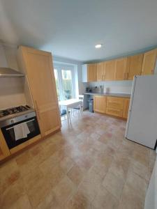 a kitchen with wooden cabinets and a white refrigerator at Cosy Brighouse 3 bed house-Great for contractors in Brighouse