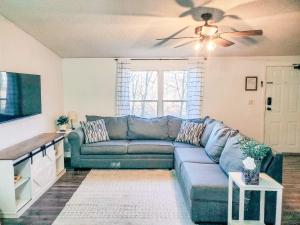 ein Wohnzimmer mit einem blauen Sofa und einem Deckenventilator in der Unterkunft Tucky Cabin - Riverfront Getaway in Fentress McMahan