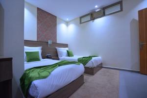 Habitación de hotel con 2 camas con sábanas verdes en RESIDENCE CENTROSUIT, en Laayoune