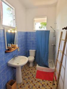 W wyłożonej niebieskimi kafelkami łazience znajduje się toaleta i umywalka. w obiekcie Villa Sunshine w mieście La Trinité