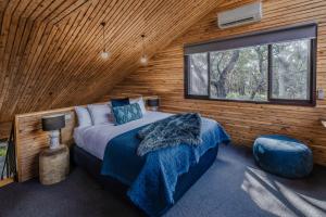 Dormitorio con cama y ventana en una cabaña de madera en DULC Cabins, en Halls Gap