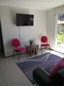 ein Wohnzimmer mit 2 roten Stühlen und einem TV in der Unterkunft Departamento Pucón Nativo in Pucón