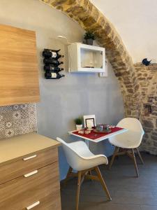 una cucina con tavolo, 2 sedie bianche e bottiglie di vino di Domus Relax a Pietrelcina