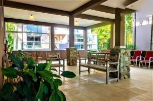 un hall avec des bancs, des tables et des fenêtres dans l'établissement Ilhabela - Praia do Curral - Casa em condomínio, à Ilhabela