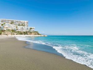 una playa con dos edificios y el océano en Luxury complex beachfront apartment with gym and large terrace, en Torremolinos