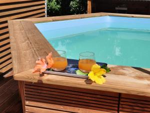 due bicchieri di succo su un vassoio accanto a una piscina di Cottages Les Ventilés a Deshaies