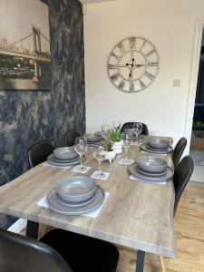 einen Tisch mit Tellern und Weingläsern sowie eine Uhr in der Unterkunft 6 Stephenson Way in York