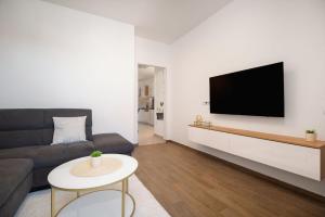 a living room with a couch and a tv on a wall at Apartman Kiara in Rogoznica