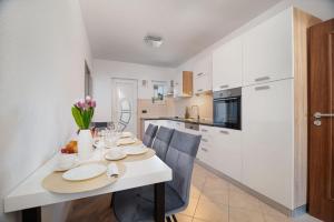 a kitchen and dining room with a white table and chairs at Apartman Kiara in Rogoznica