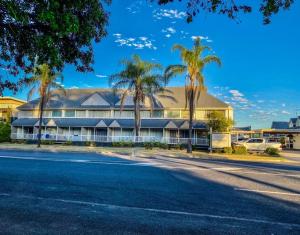 a building with palm trees in front of a street at Dalby Manor Motor Inn in Dalby