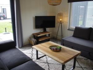 uma sala de estar com um sofá e uma mesa de centro em Beautiful bungalow with bath, located in a holiday park near the city of Alkmaar em Hensbroek