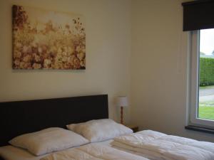 um quarto com uma cama e um quadro na parede em Beautiful bungalow with bath, located in a holiday park near the city of Alkmaar em Hensbroek