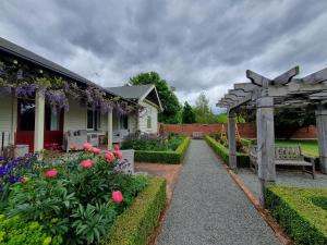 um jardim com um banco e uma pérgola e flores em Hurunui Homestead Bed and Breakfast em Hawarden