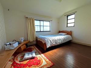 1 dormitorio con cama, ventana y alfombra en 日久の宿 en Kokubunji