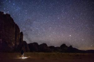 a man standing in the desert under a starry sky at Stargazing Camp & Tours in Wadi Rum