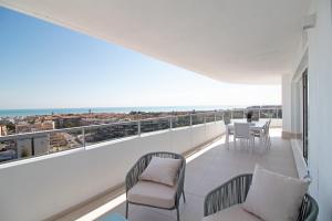 een balkon met een tafel en stoelen en uitzicht op de oceaan bij Global Properties, Moderno apartamento con vistas a la costa mediterranea en Gran Canet in Canet de Berenguer