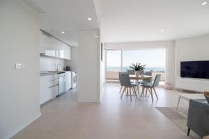 uma cozinha branca e sala de jantar com mesa e cadeiras em Global Properties, Moderno apartamento con vistas a la costa mediterranea en Gran Canet em Canet d'En Berenguer