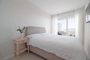 een witte slaapkamer met een bed en een raam bij Global Properties, Moderno apartamento con vistas a la costa mediterranea en Gran Canet in Canet de Berenguer