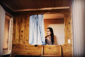 Eine Frau, die aus einem Fenster in einer Hütte schaut. in der Unterkunft ゲストハウス喜舎場 in Ishigaki-jima