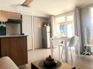 eine Küche und ein Esszimmer mit einem Tisch und einem Kühlschrank in der Unterkunft MH Luxury Eden Mar Estang Plage 100m 2TV 2 Sdb Baby confort Plus in Canet-en-Roussillon