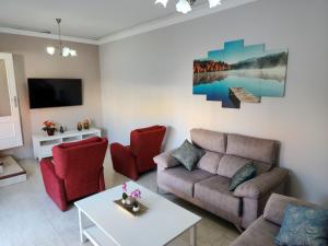 a living room with a couch and red chairs at Casa Marta. in Granadilla de Abona