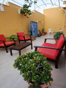 a patio with red chairs and tables and plants at Casa Marta. in Granadilla de Abona