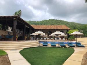 a resort with chairs and umbrellas and a swimming pool at Casa de la Costa in Troncones