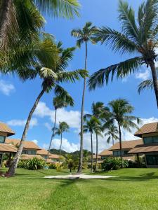 a group of palm trees in front of a resort at Casa em Carneiros - 4 suítes com piscina in Tamandaré